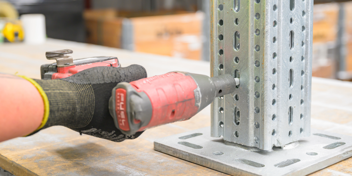 Sikla beam placed on a table with a red impact driver adding a self forming screw to connect the steel beam to the footplate